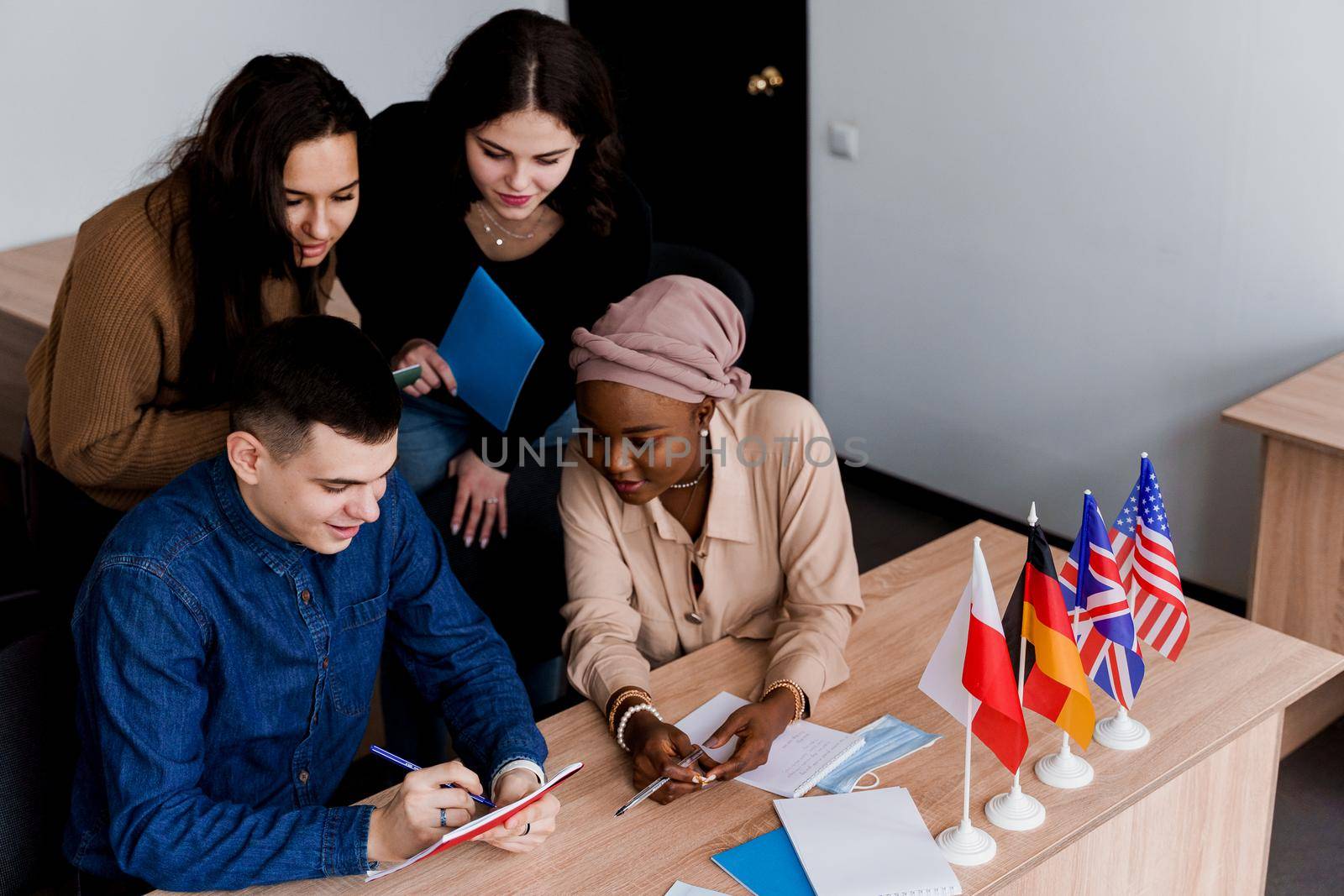 English class study with students from diffent countries: Poland, Germany, USA. Teamwork. Working in multiethnic students. Teacher study foreign languages together in class. Studing with laptop by Rabizo