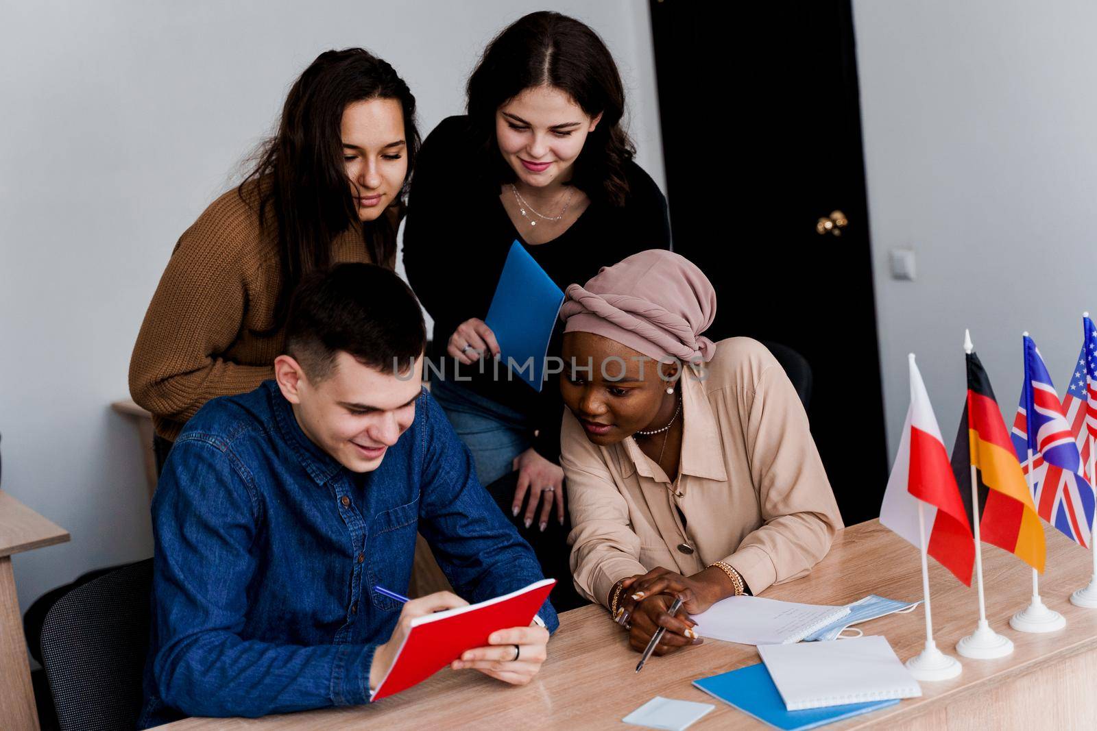 English class study with students from diffent countries: Poland, Germany, USA. Teamwork. Working in multiethnic students. Teacher study foreign languages together in class. Studing with laptop.