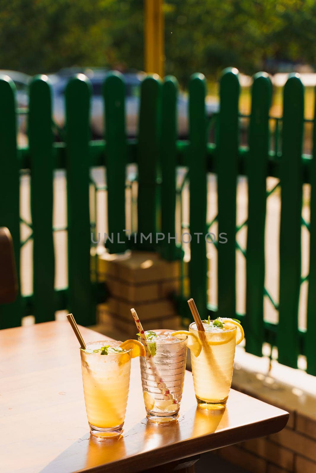 Cocktails with lemon and mint in glasses with tube on a wooden table against the background of a restaurant. Cold lemonade