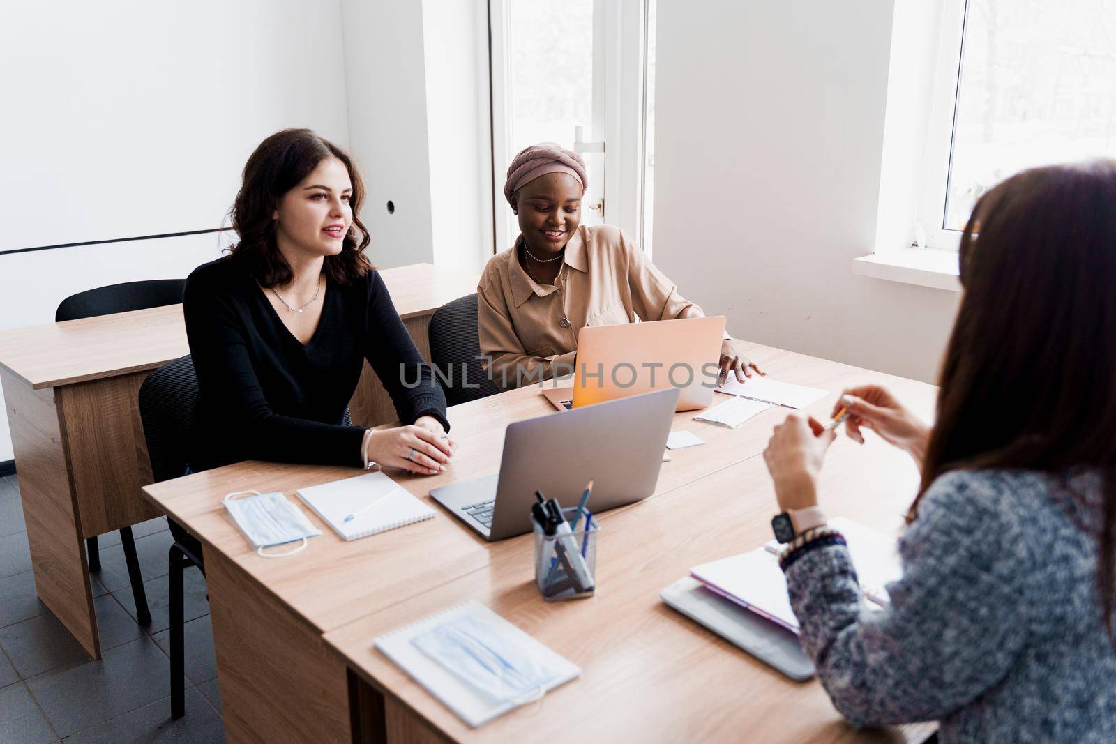 Multiethnic students and teacher study foreign languages together in class. Studing with laptop. Black handsome girl student study with white people together and look into camera