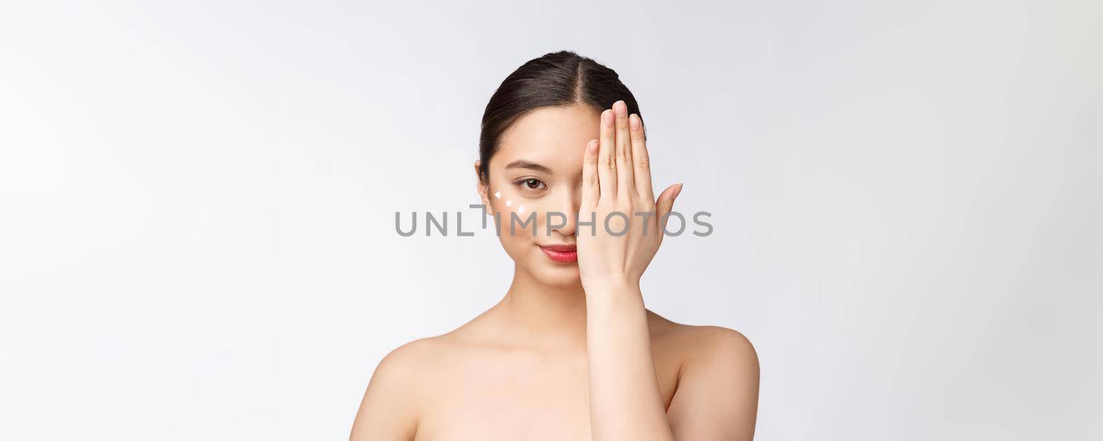 Skin care beauty woman. Beauty woman smiling applying cream. Beauty portrait of beautiful Asian Caucasian female model isolated on white