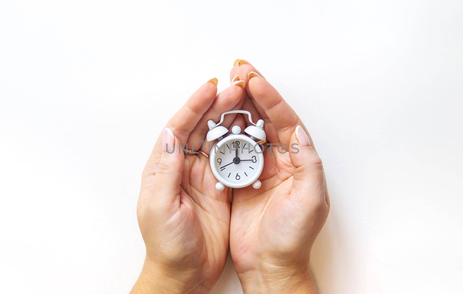 Alarm clock in hands on a white background. Selective focus. by mila1784