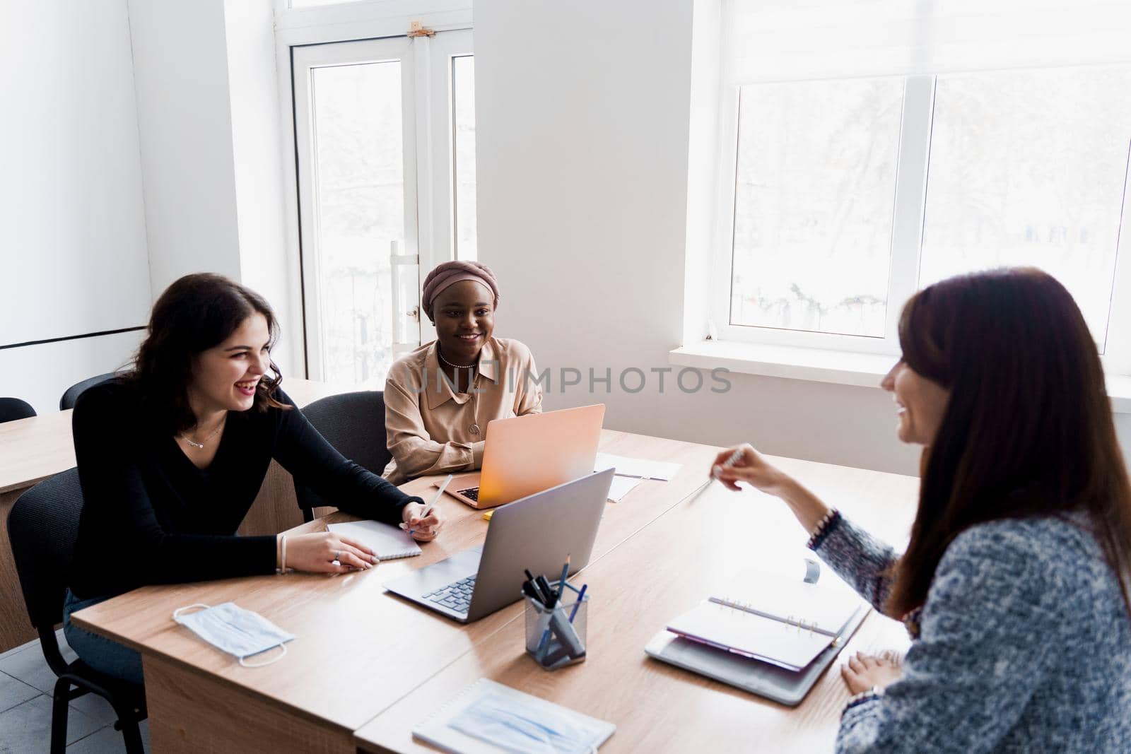 Multiethnic students and teacher study foreign languages together in class. Studing with laptop. Black handsome girl student study with white people together and look into camera