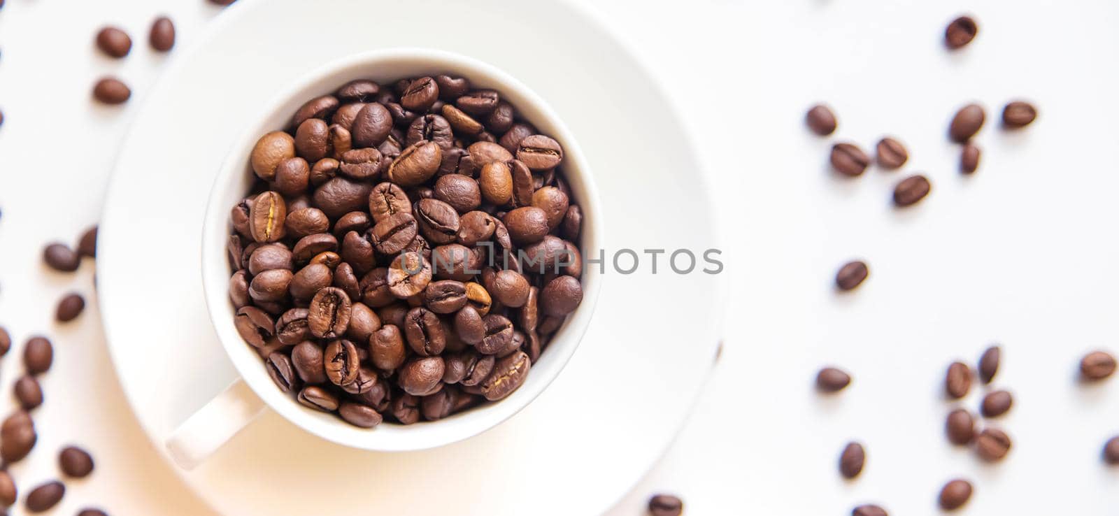 white cup and coffee beans on a white background. Selective focus.