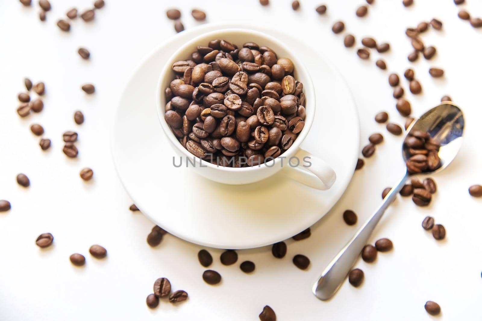 white cup and coffee beans on a white background. Selective focus.