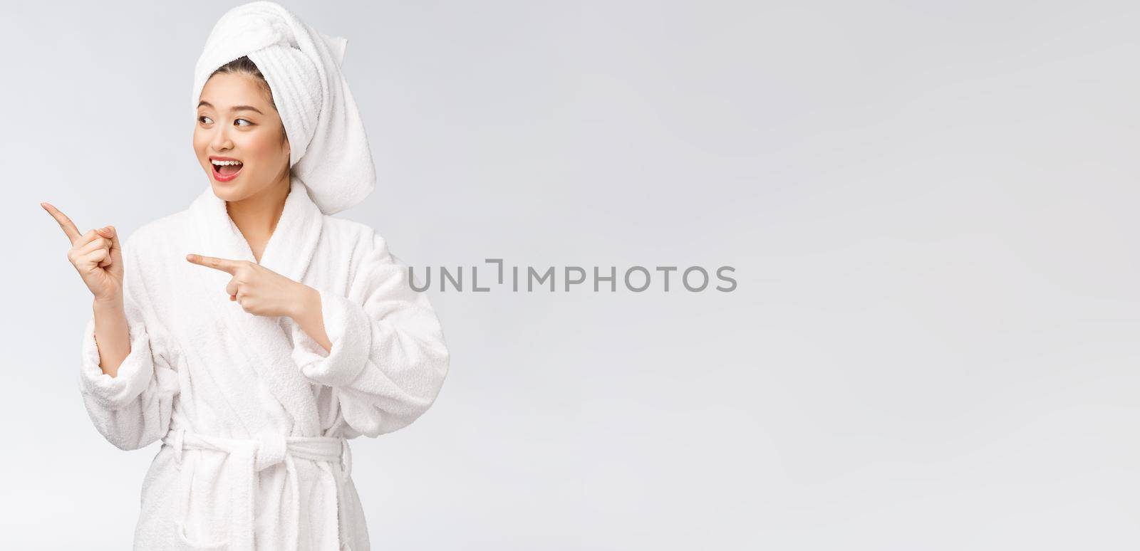 Beauty portrait of young woman showing and pointing finger to empty copy space, asian beauty in bathrobe