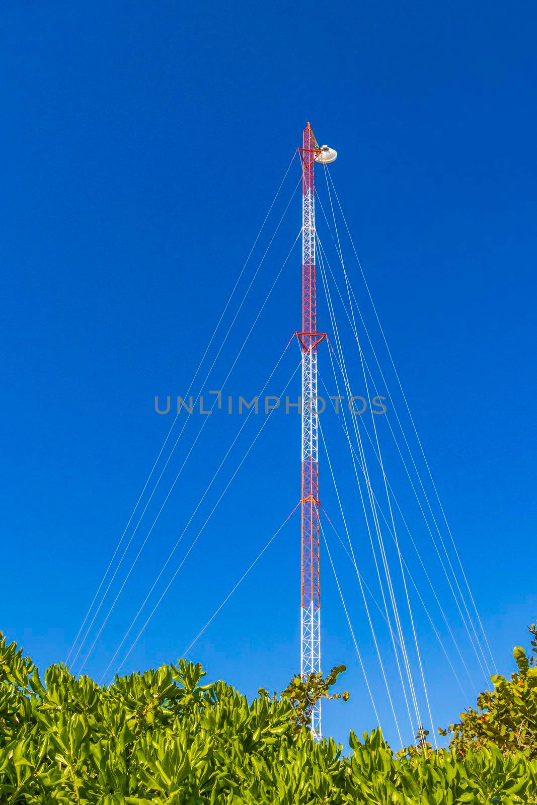 Red white 5G tower with blue sky background radiation kills us in Tulum in Mexico.