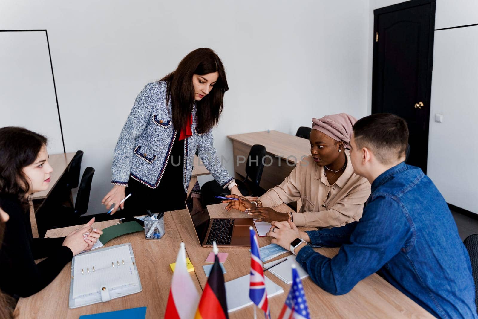 Foreign school private study with a school girl. Teacher explain grammar of native language using laptop. Prepearing to exam with tutor. English, British, German and Poland flags in front by Rabizo