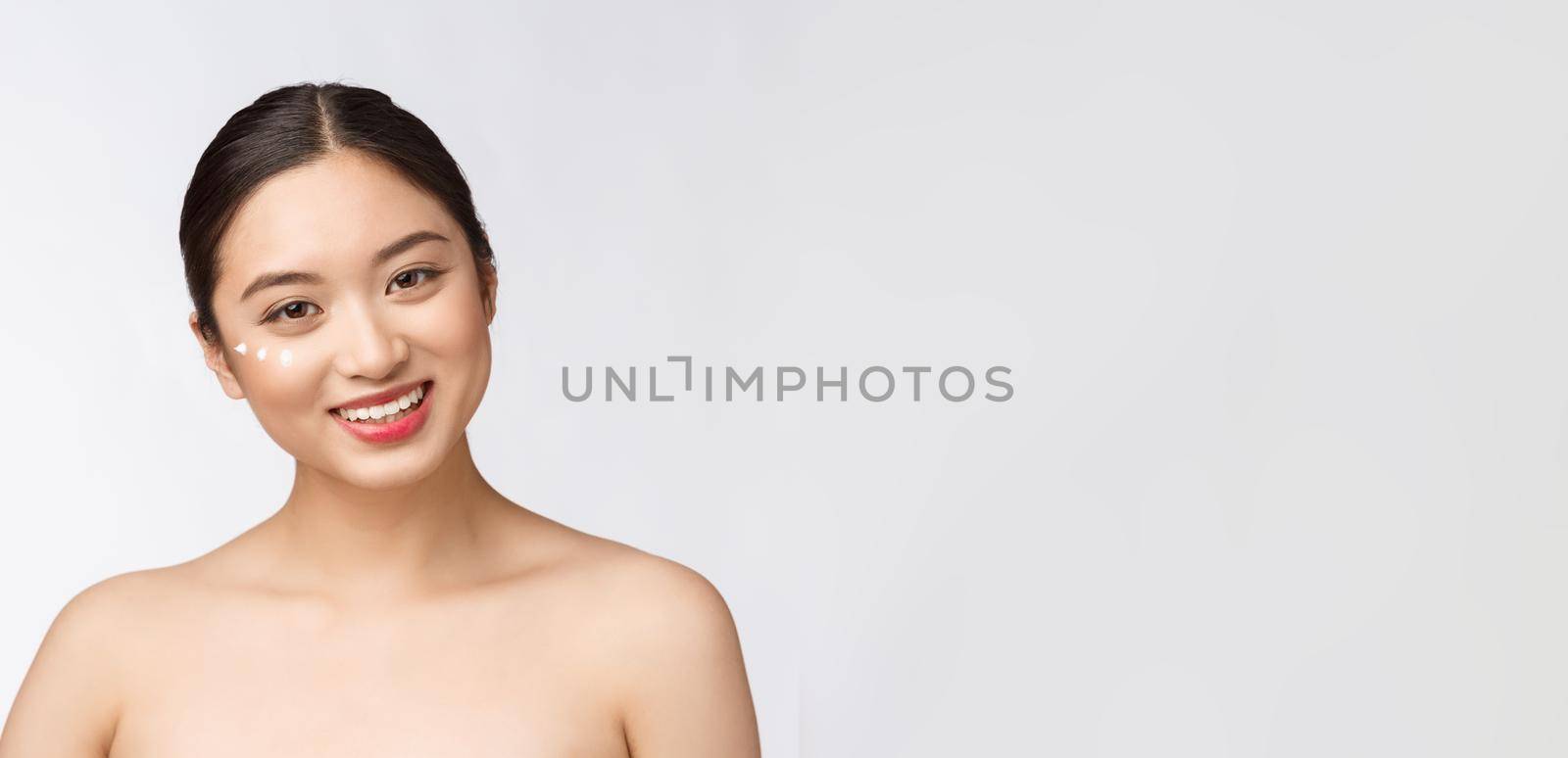 Skin care beauty woman. Beauty woman smiling applying cream. Beauty portrait of beautiful Asian Caucasian female model isolated on white