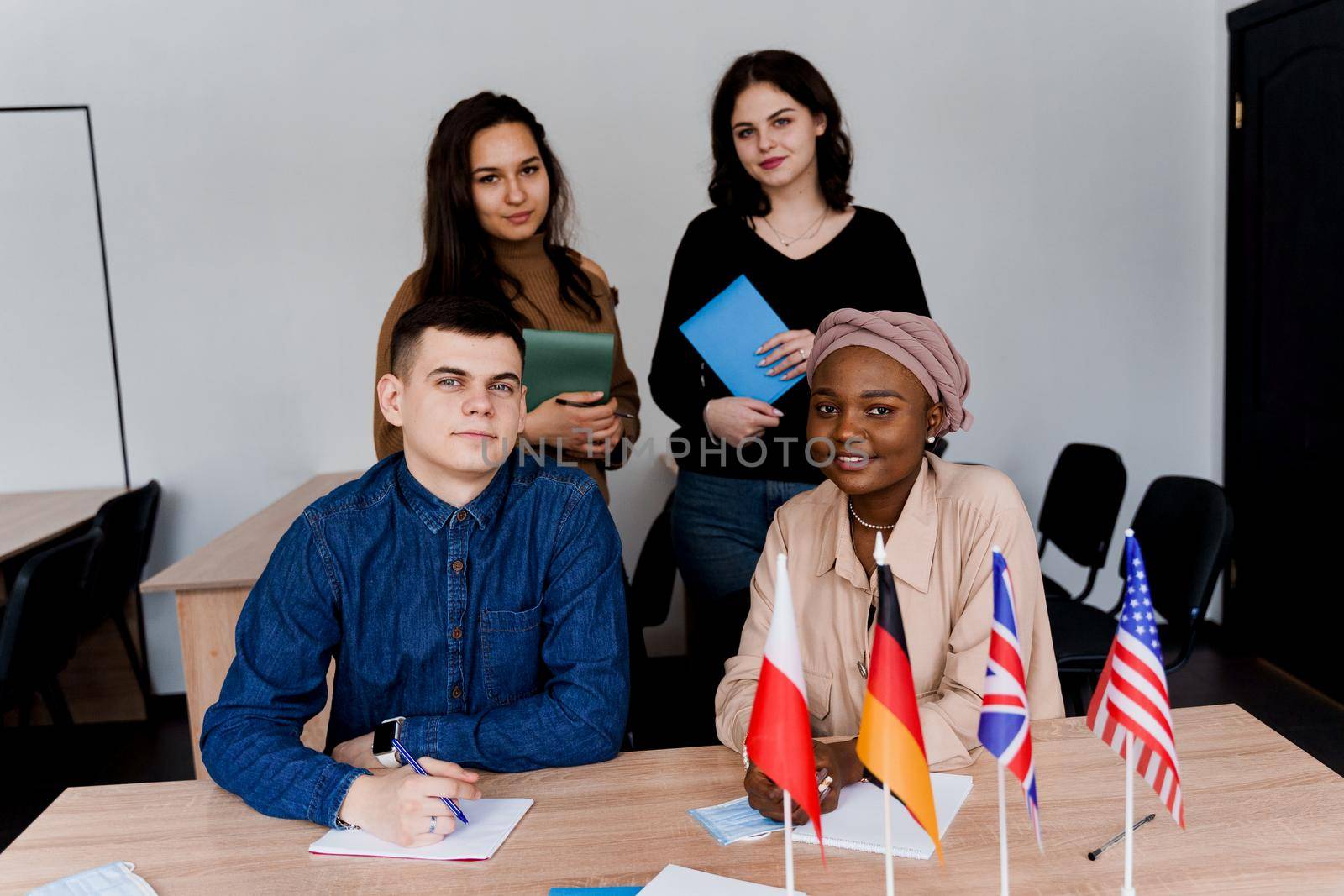 Teamwork. Working in multiethnic group of students. teacher study foreign languages together in class. Studing with notebook. Black handsome girl student study with white people together. by Rabizo