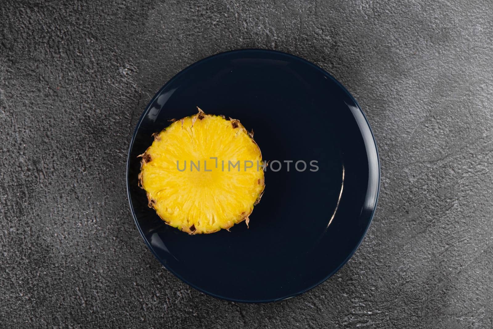 Piece of pineapple on blue plate close-up. Slice of yellow tropical fruit.