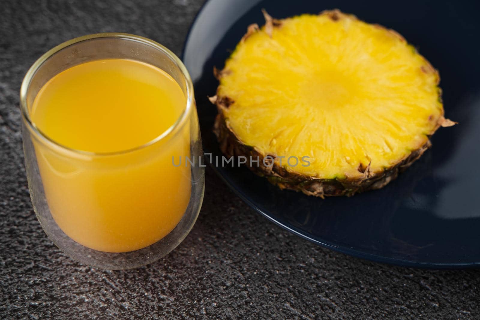 Piece of pineapple tropical fruit and yellow juice on dark background. by Rabizo