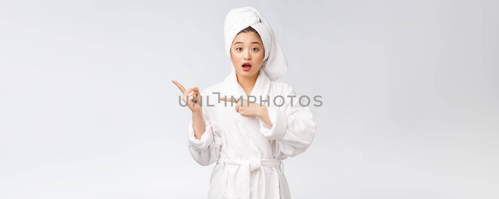 Beauty portrait of young woman showing and pointing finger to empty copy space, asian beauty in bathrobe