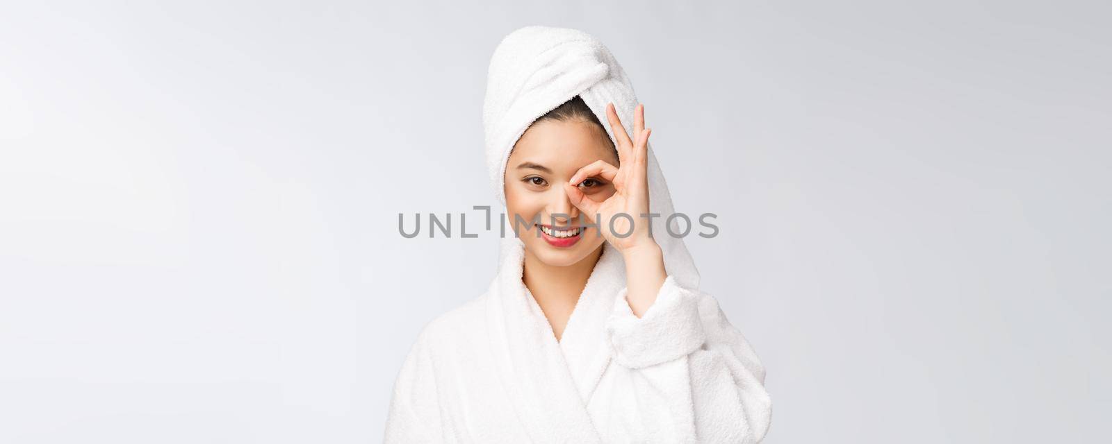 Close up of young smiling woman with finger ok gesture on eyes, isolated on white background.