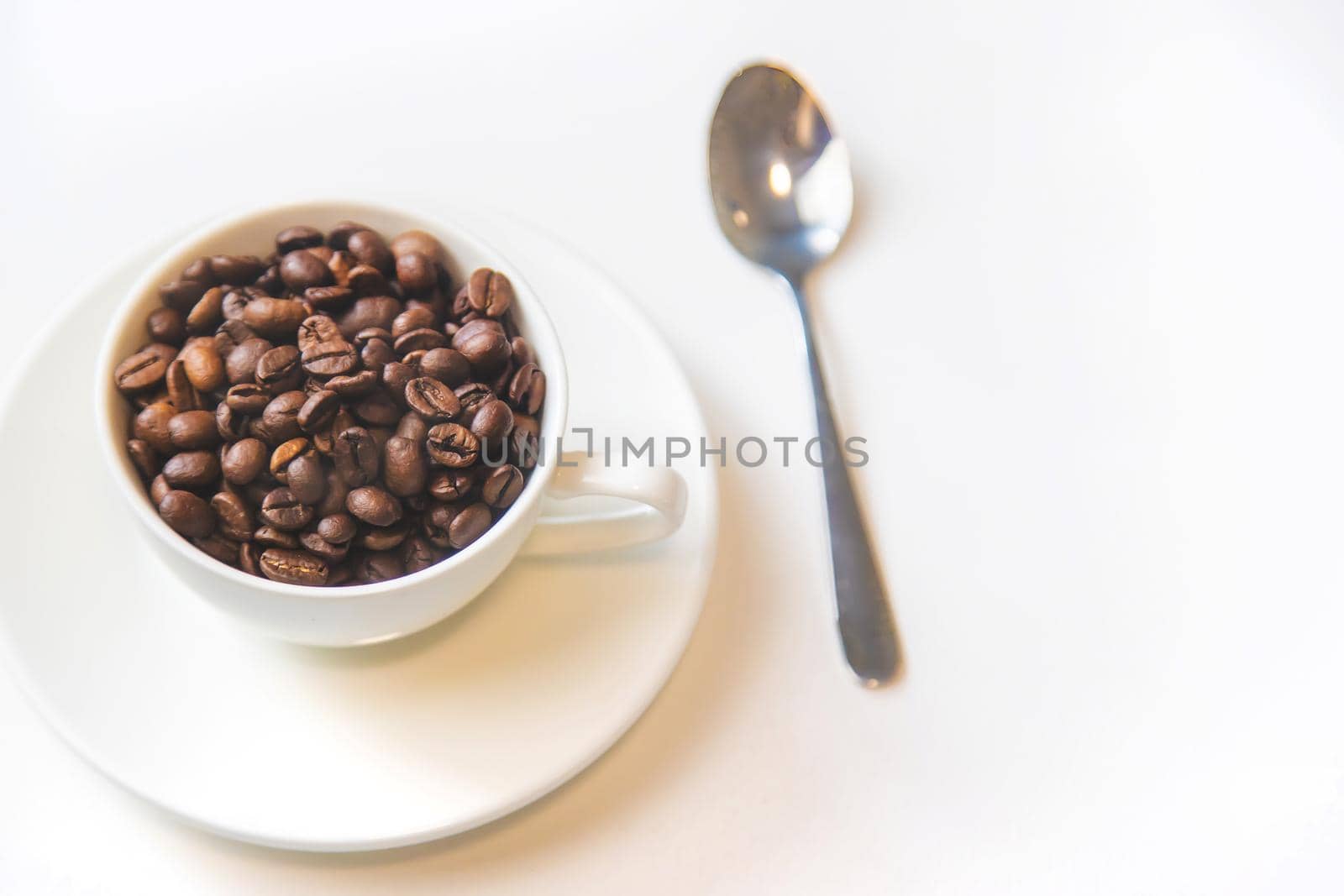 white cup and coffee beans on a white background. Selective focus.