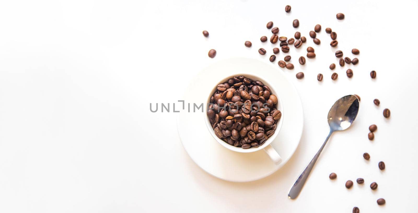 white cup and coffee beans on a white background. Selective focus.