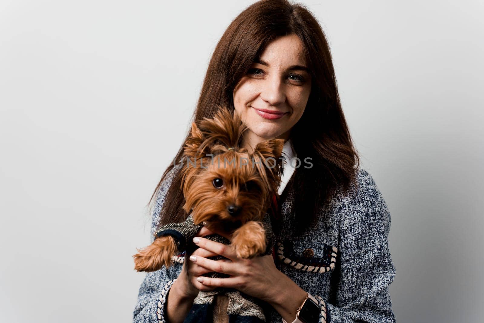 Young attractive woman with dog yorkshire terrier smiles. Close up photo. Pet care. People and pets. Girl holds brown dog isolated on white background