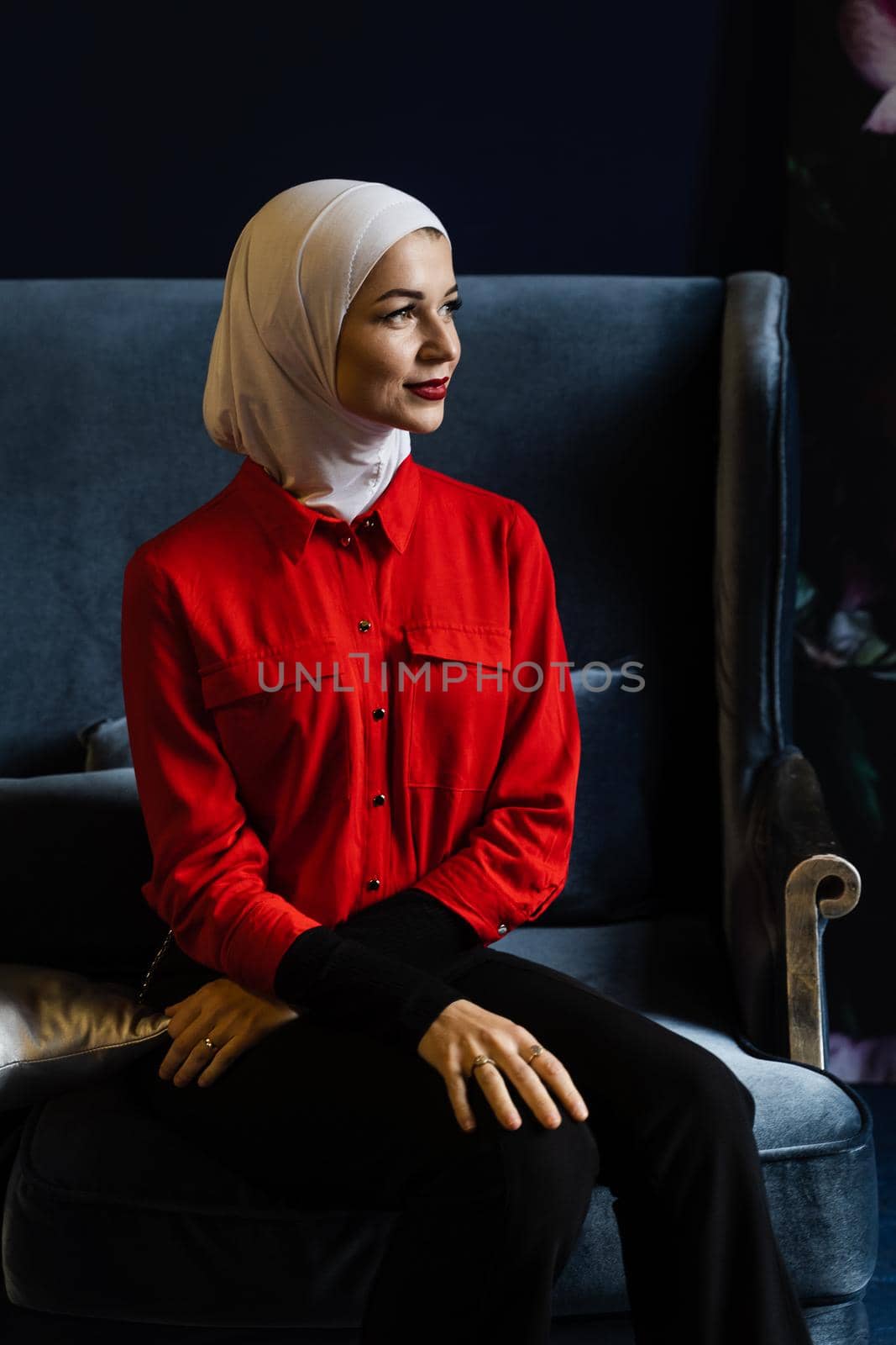 Attractive muslim caucasian girl weared head scarf is sitting on the sofa. Islam religion. by Rabizo