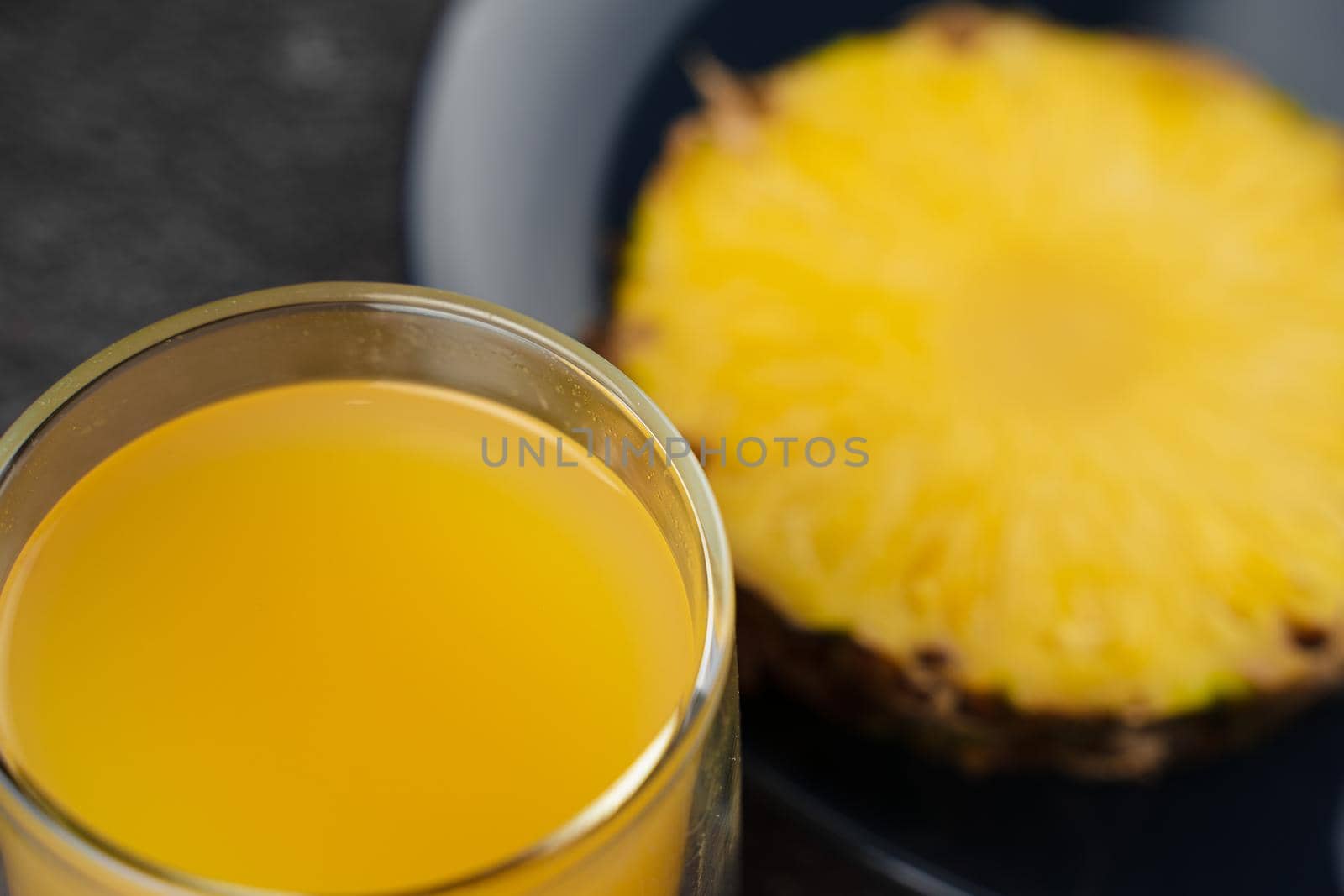Piece of pineapple tropical fruit and yellow juice on dark background