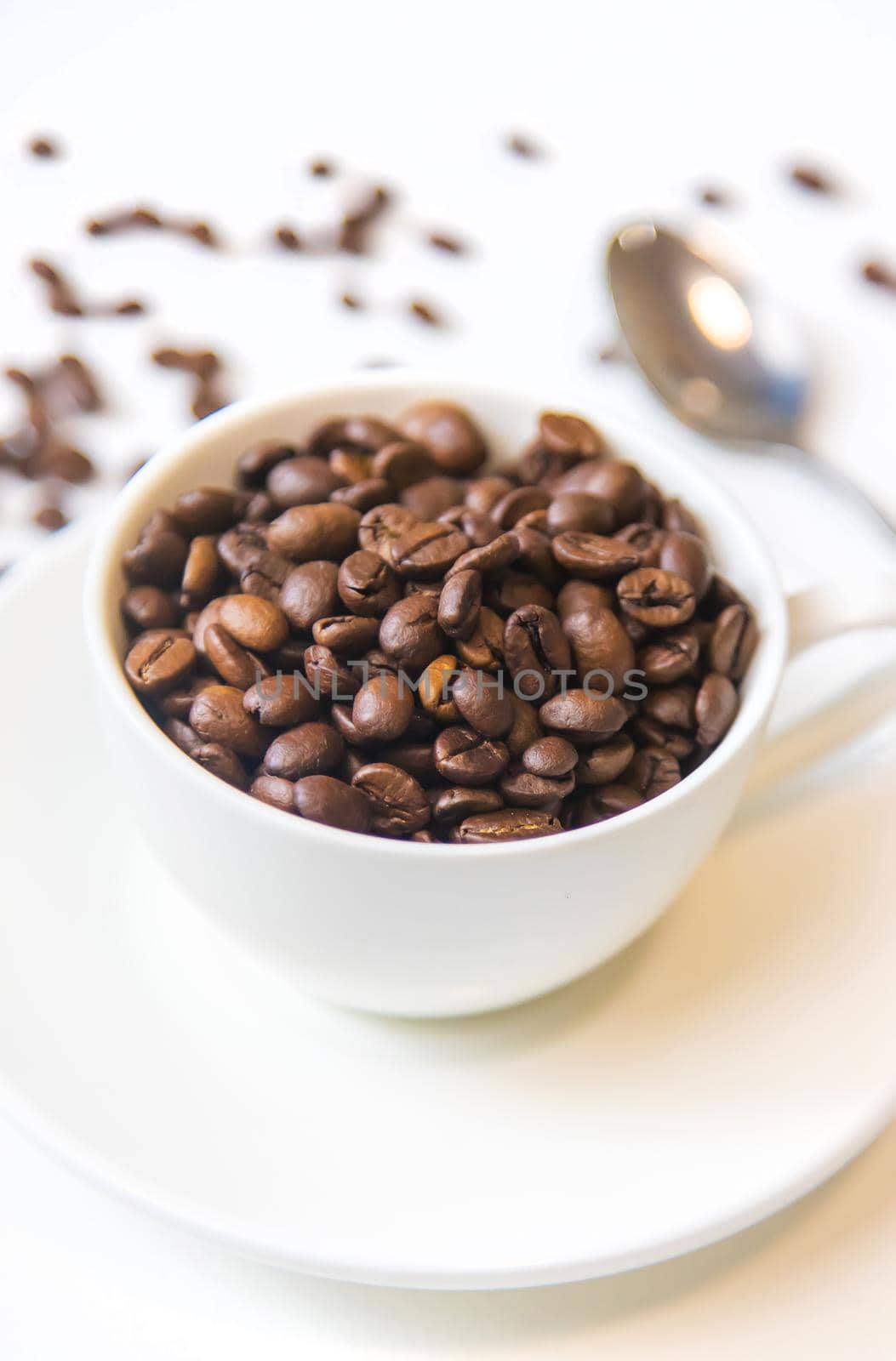 white cup and coffee beans on a white background. Selective focus.