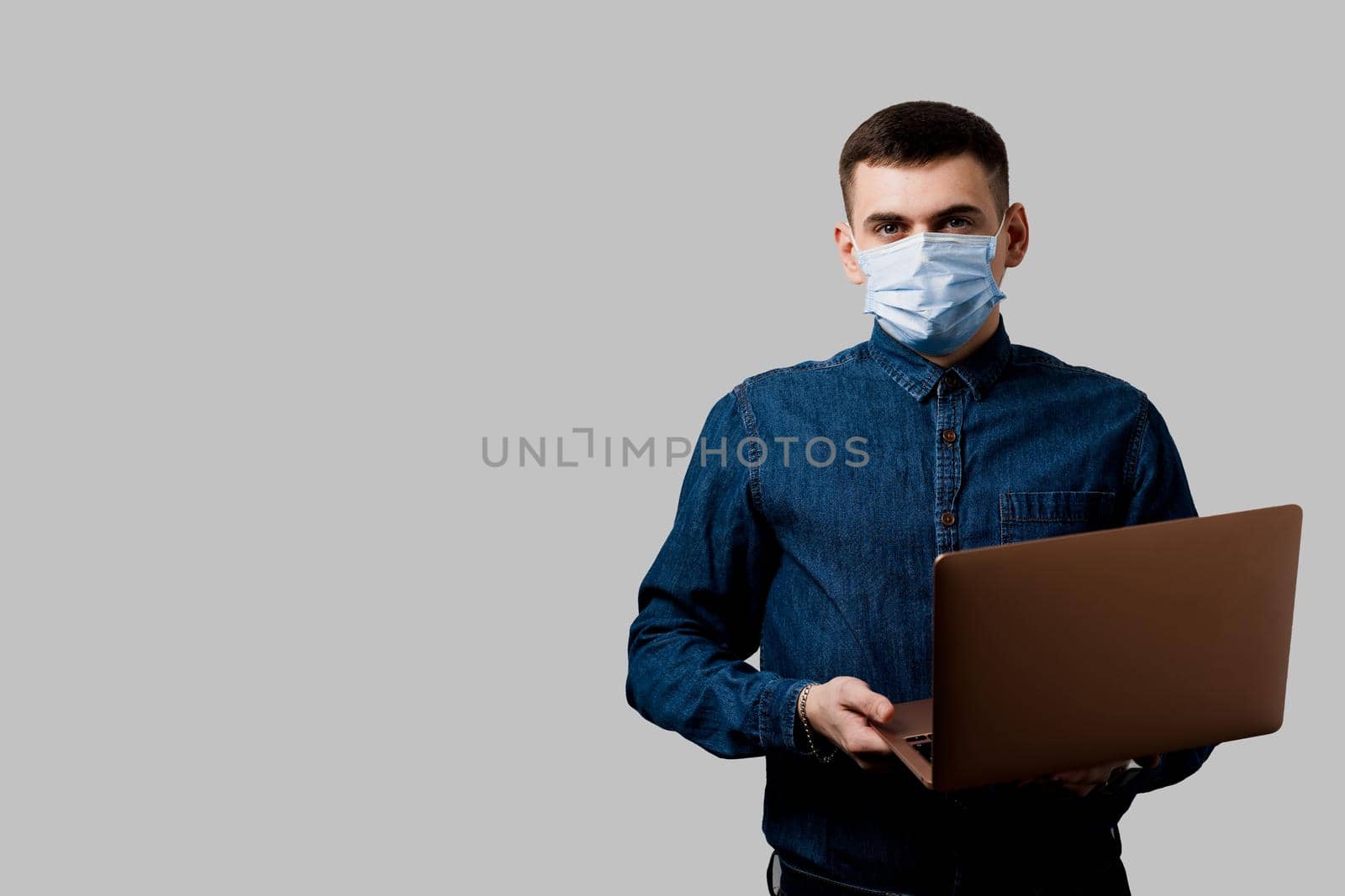 Education and working on-line at quarantine coronavirus covid-19 period. Man in medical mask with laptop on black background.