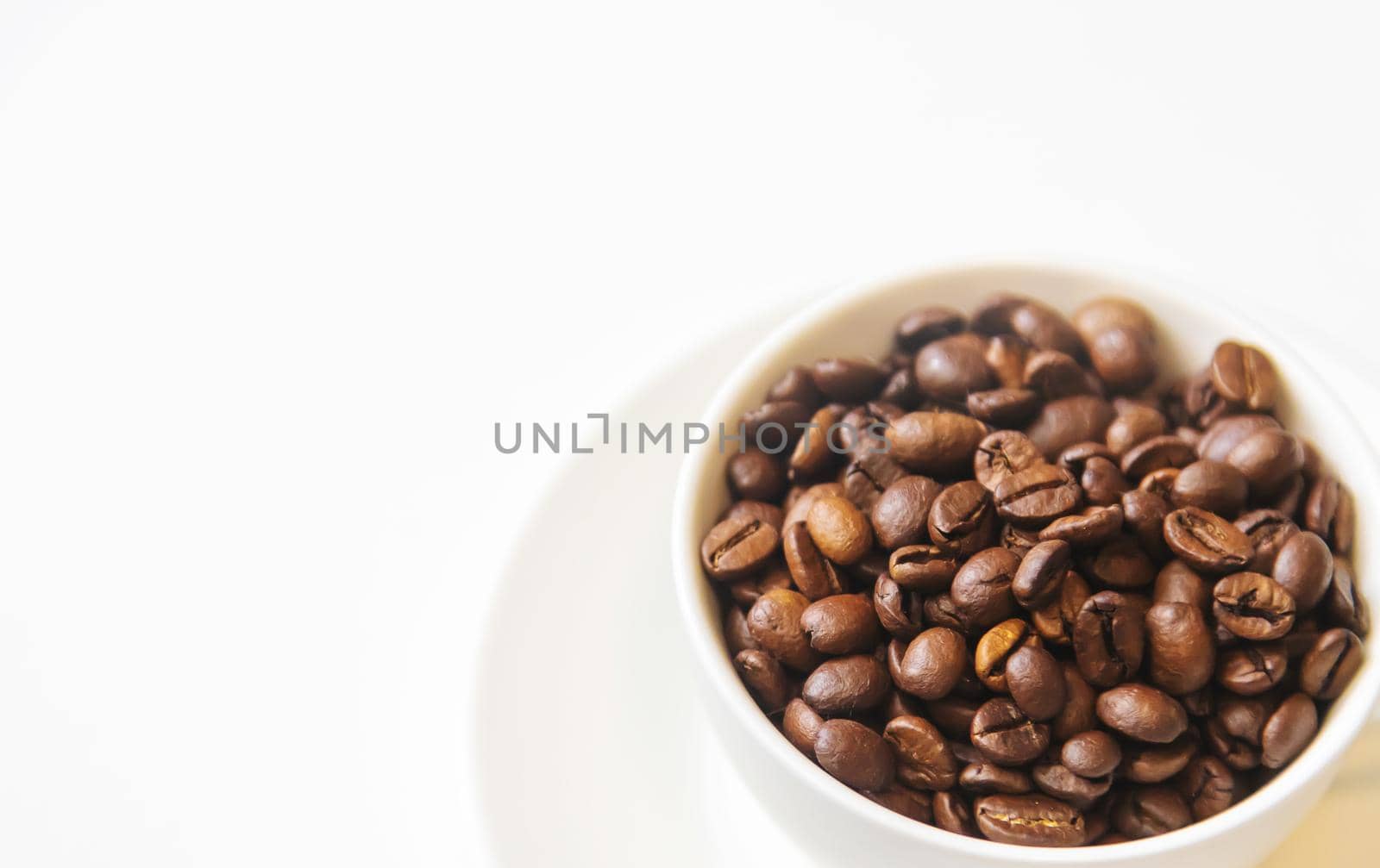 white cup and coffee beans on a white background. Selective focus.