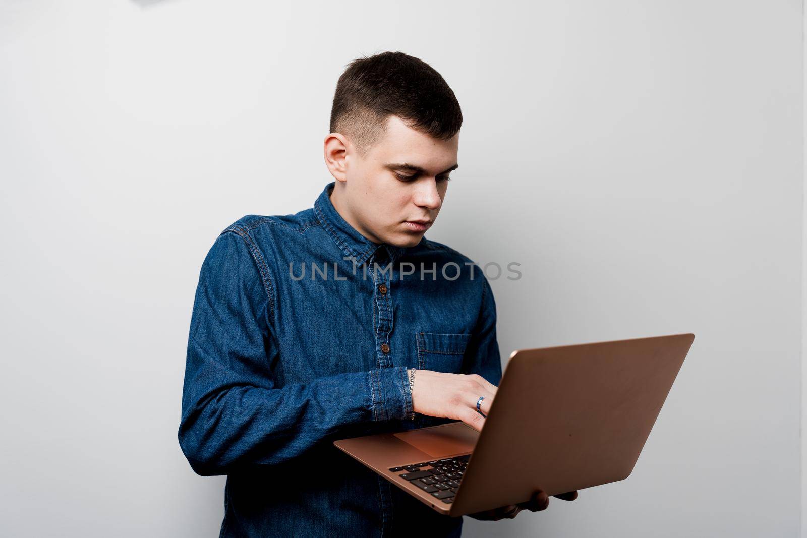 Handsome man with laptop on the gray background. Business man working online at home by Rabizo