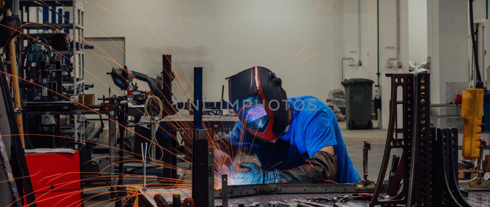 Professional Heavy Industry Welder Working Inside the factory, Wears Helmet and Starts Welding. Selective Focus. High-quality photo