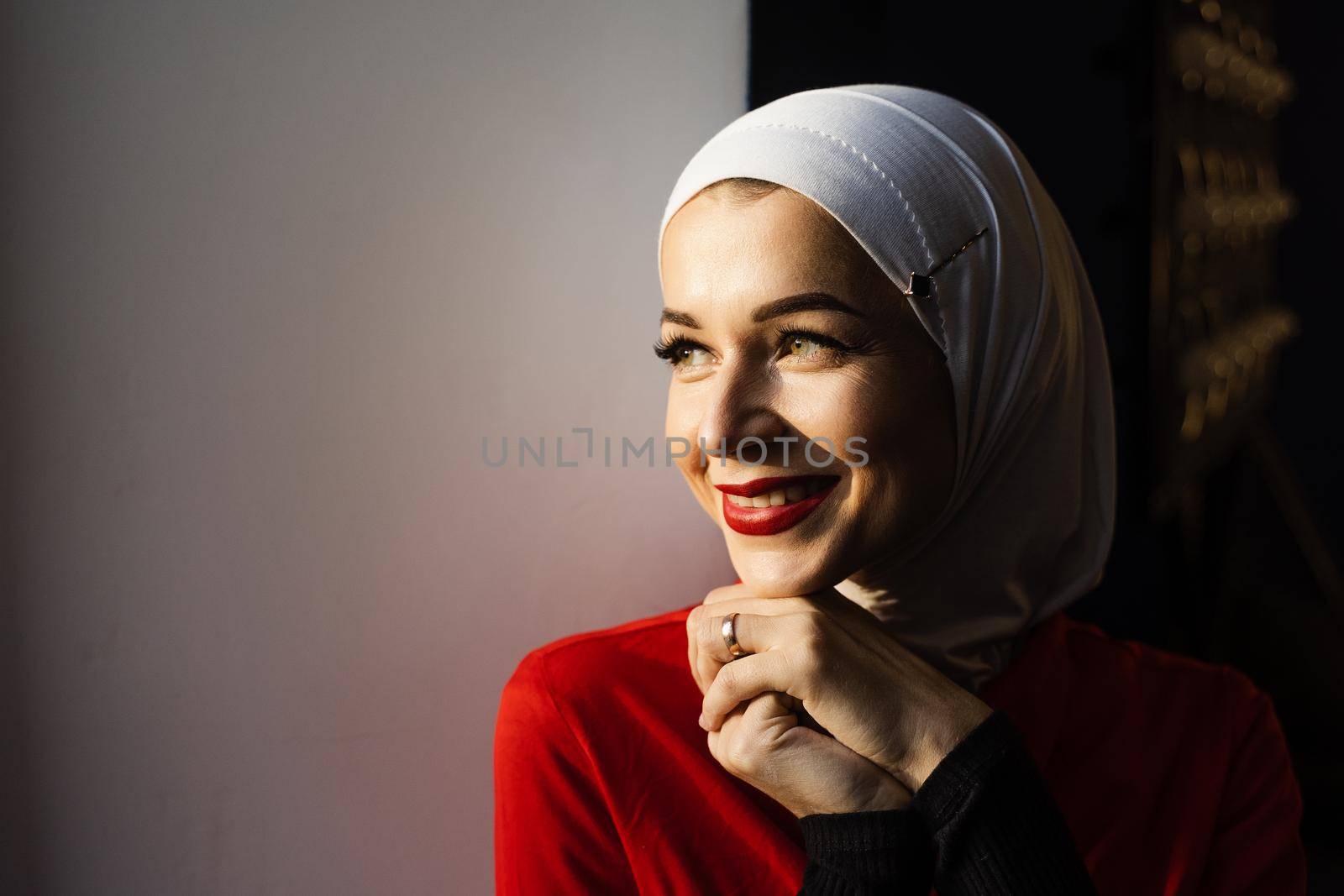 Muslim girl is smiling at home. Close-up portrait of muslim model weared in traditional islamic scarf. Islam religion. by Rabizo
