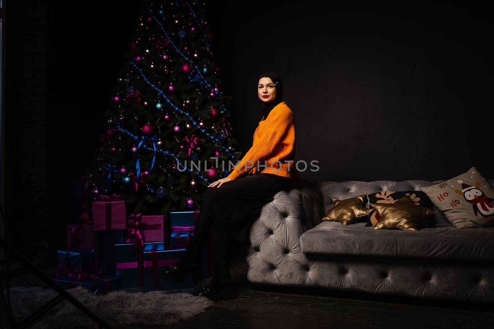 Muslim woman in black hijab near new year tree waiting for celebration of Christmas. Islam religion