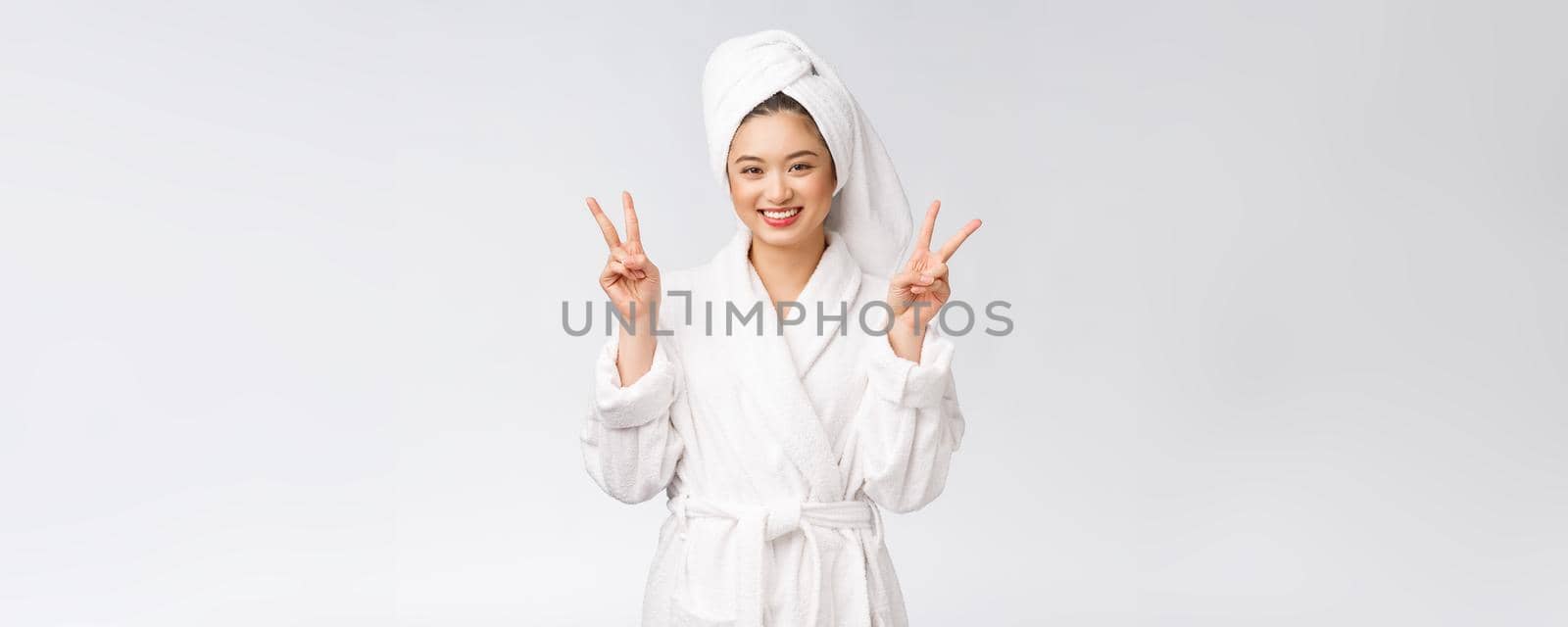 Beautiful asian woman showing peace sign or two finger with happy feeling. Isolated over white background. by Benzoix