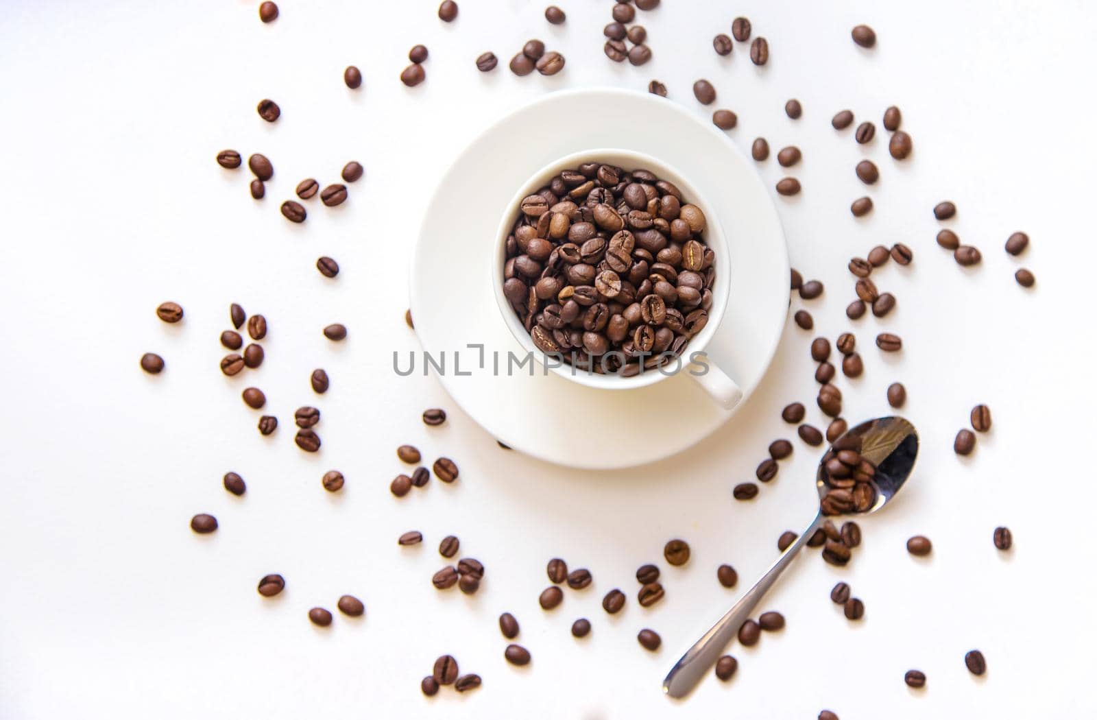 white cup and coffee beans on a white background. Selective focus.