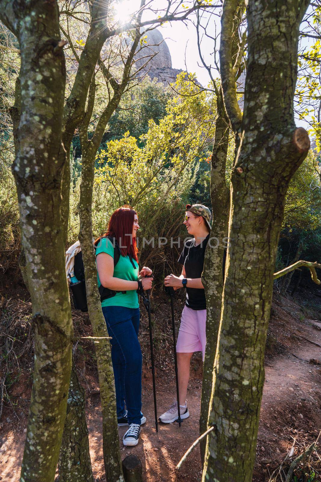 two women friends enjoying a hike in nature. young people on holiday. women standing on a mountain trail. by CatPhotography