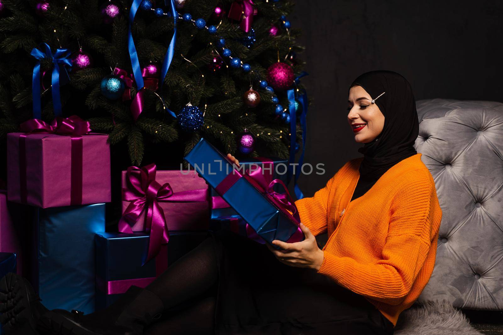 Muslim woman with gift near new year tree. Christmas celebration of islam religion people