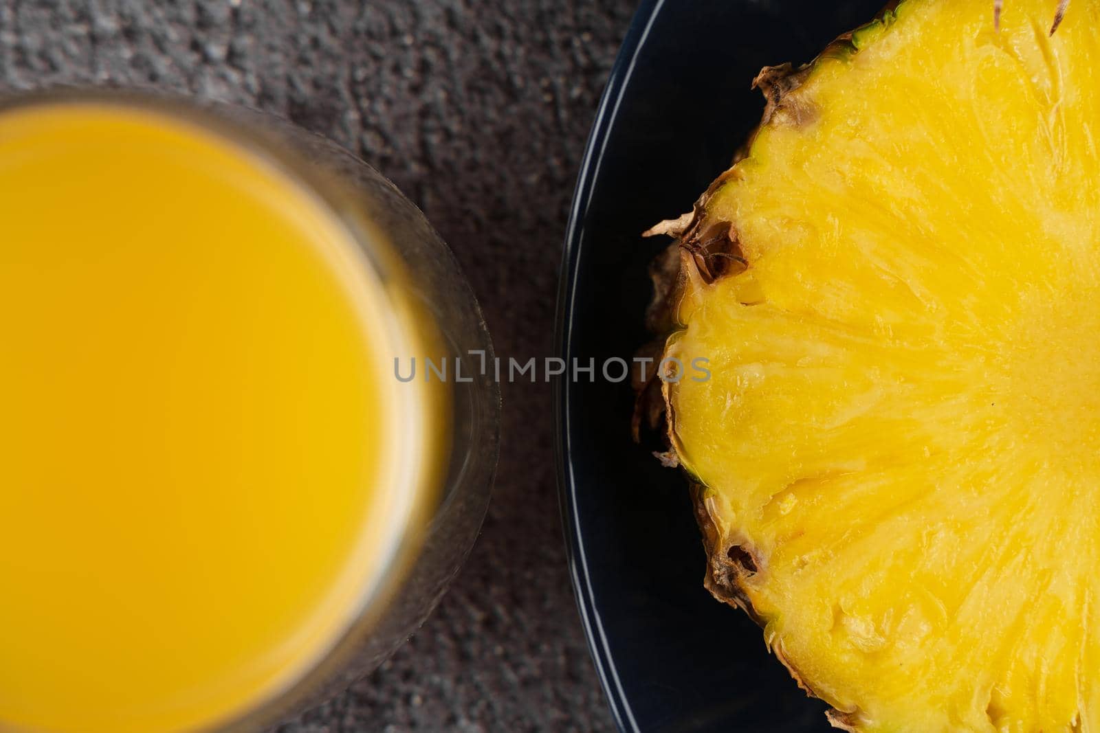 Piece of pineapple tropical fruit and yellow juice on dark background
