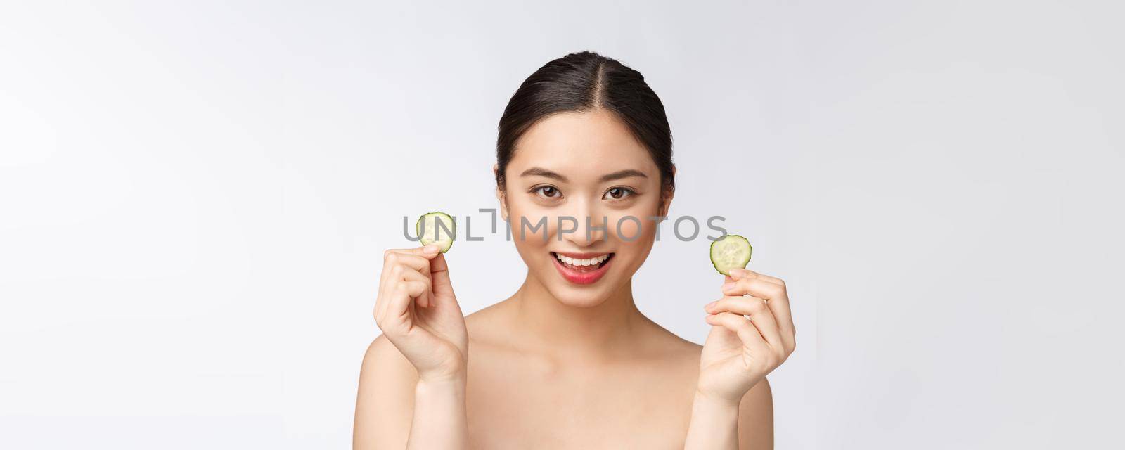 Natural homemade fresh cucumber facial eye pads facial masks. Asian woman holding cucumber pads and smile relax with natural homemade.