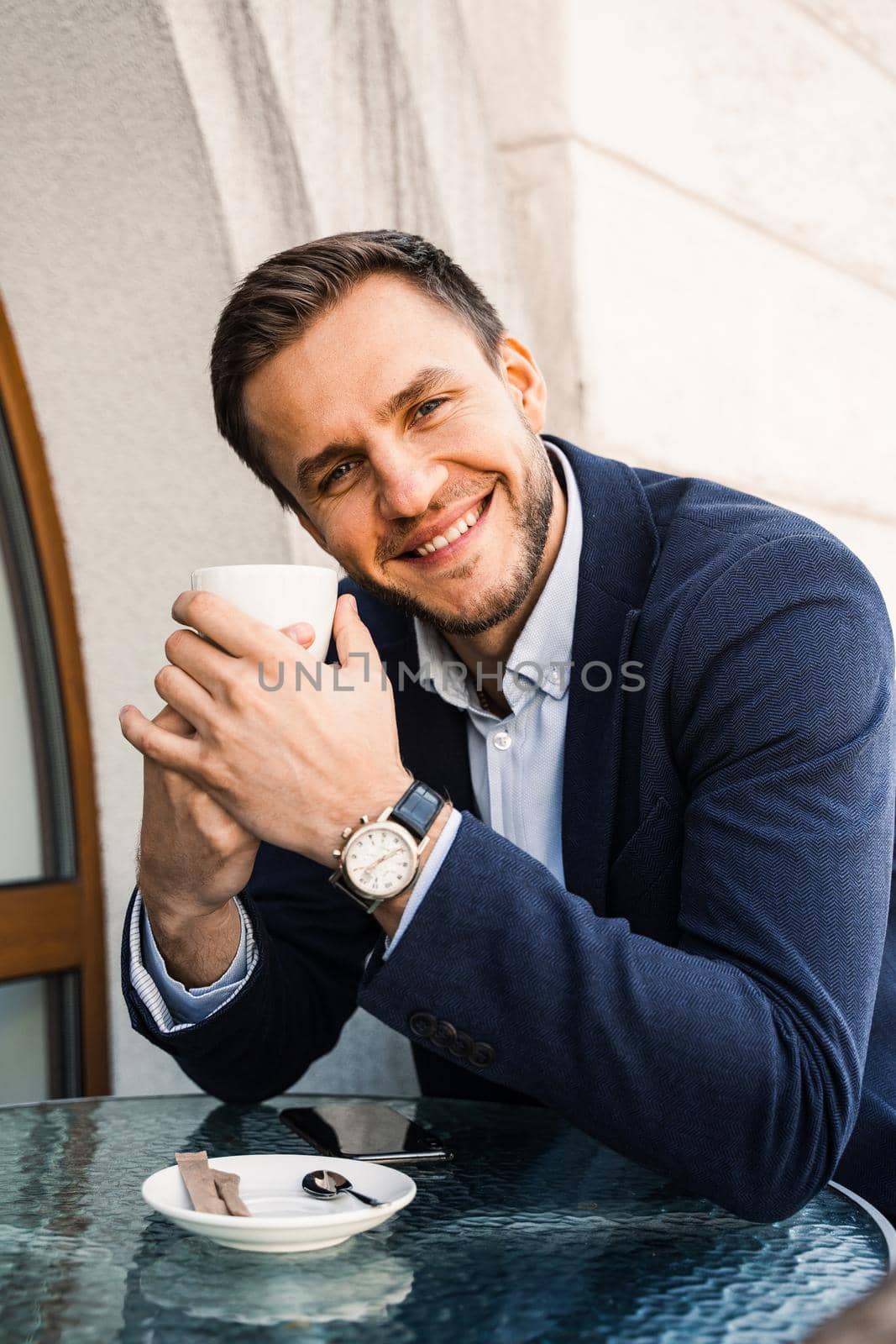 Man like coffee. Handsome man with cup of coffee in cafe. Morning lifestyle of male. Man is sitting on the summer terrace in cafe, drinking coffee and smiling