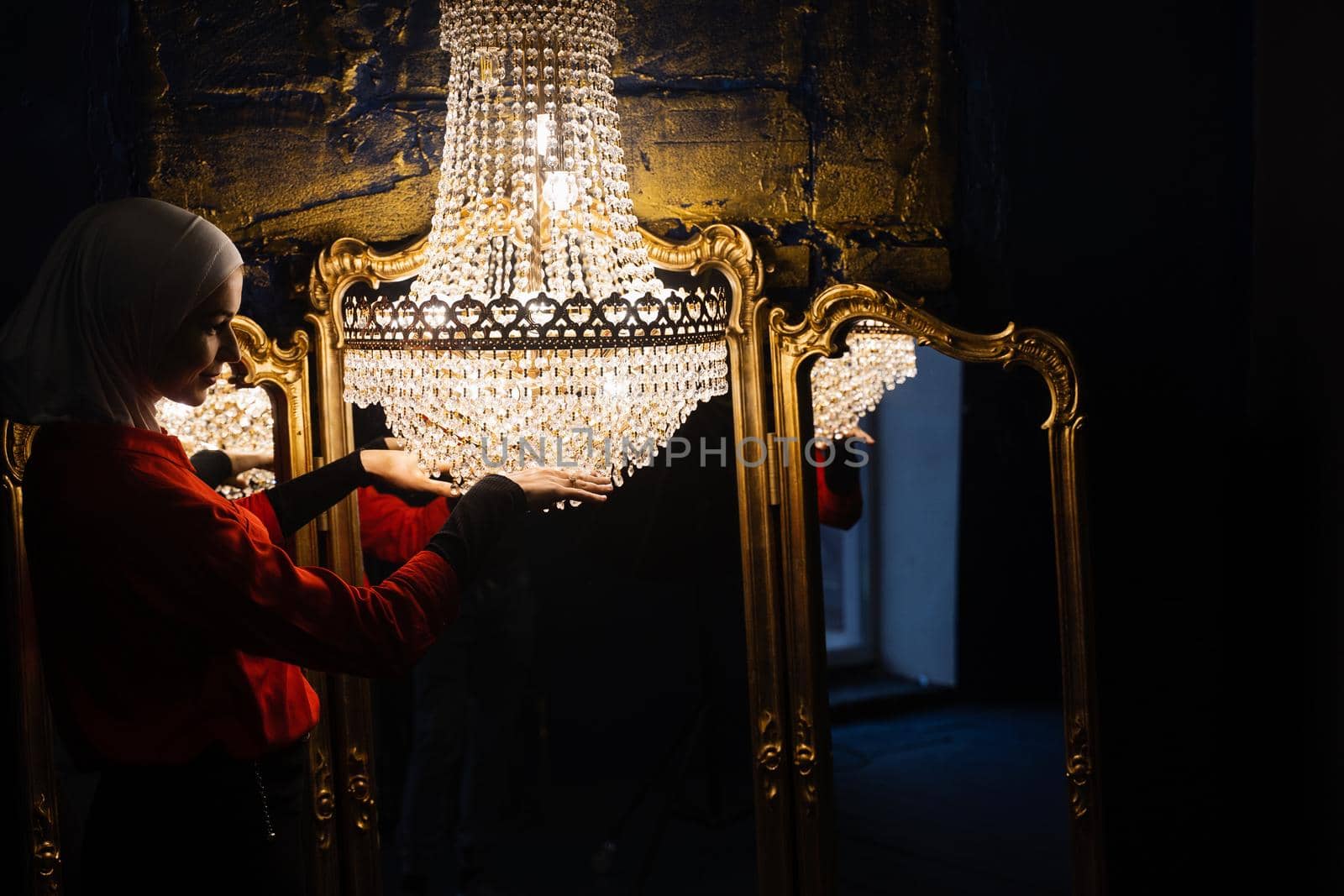 Fashion muslim model near big expensive chandelier. Islamic religion. Girl near mirrors