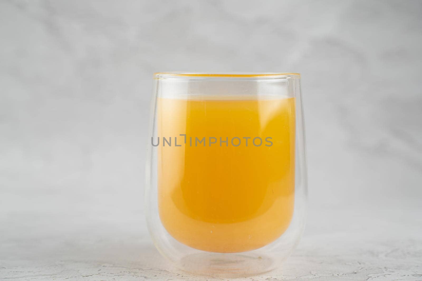 Pineapple juice in double glass cup on white stone background close-up. Isolated. by Rabizo