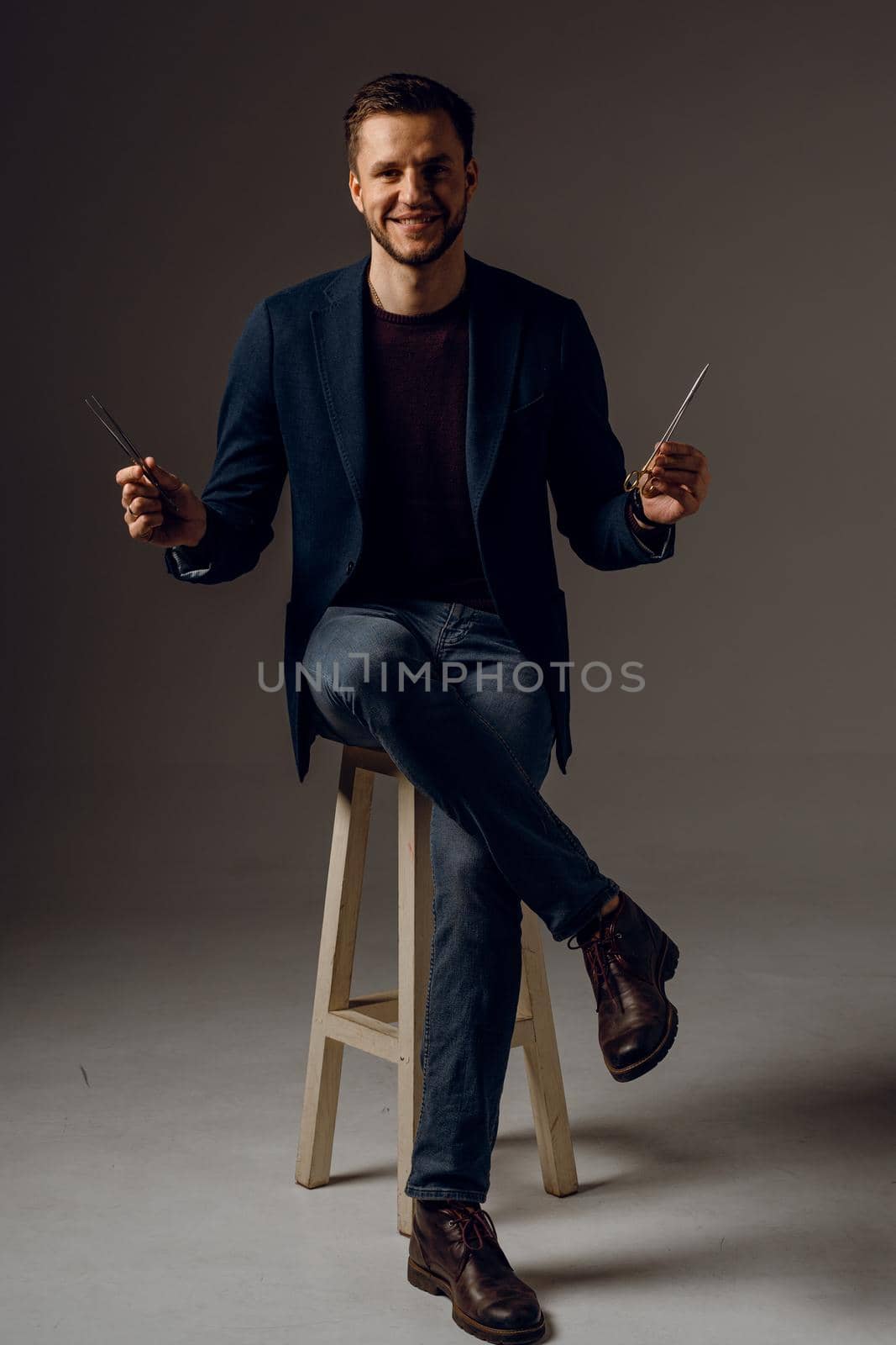 Handsome surgeon with needle holder and surgical knife weared casual suit in studio. Confident business man on dark background