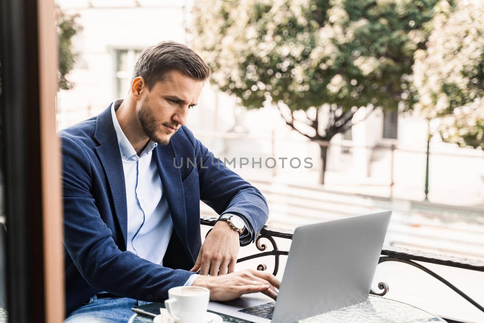 Programmer with cup of coffee is working online using laptop in cafe. Remote work