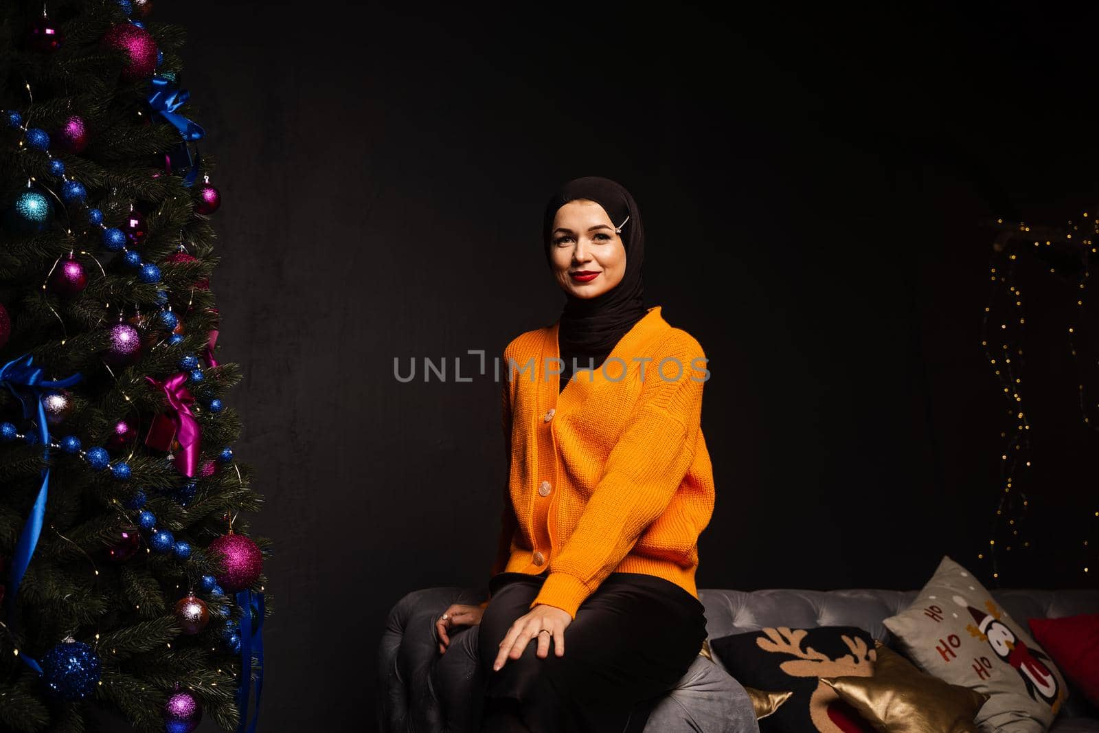 Muslim woman in black hijab near new year tree waiting for celebration of Christmas. Islam religion