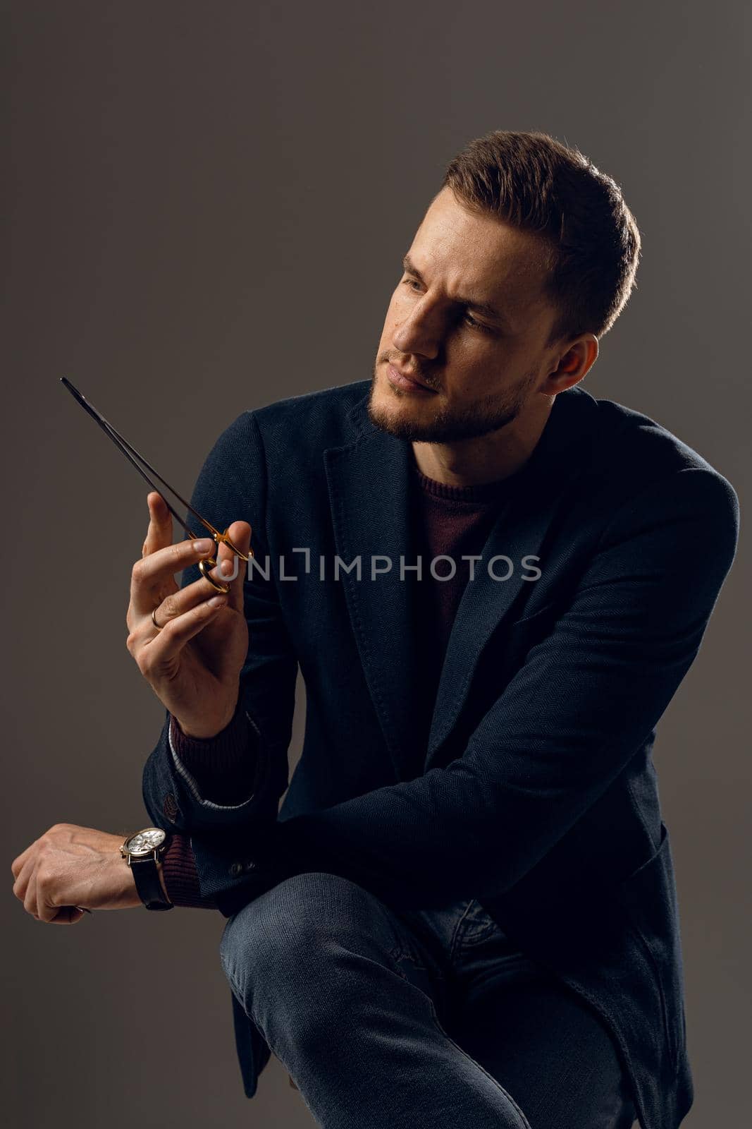 Doctor with surgical equipment needle and scissors. Handsome man weared casual business suit. Portrait of surgeon in studio