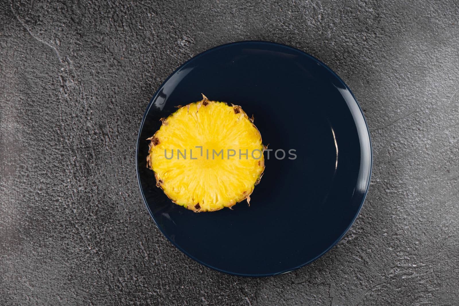 Piece of pineapple on blue plate close-up. Slice of yellow tropical fruit.