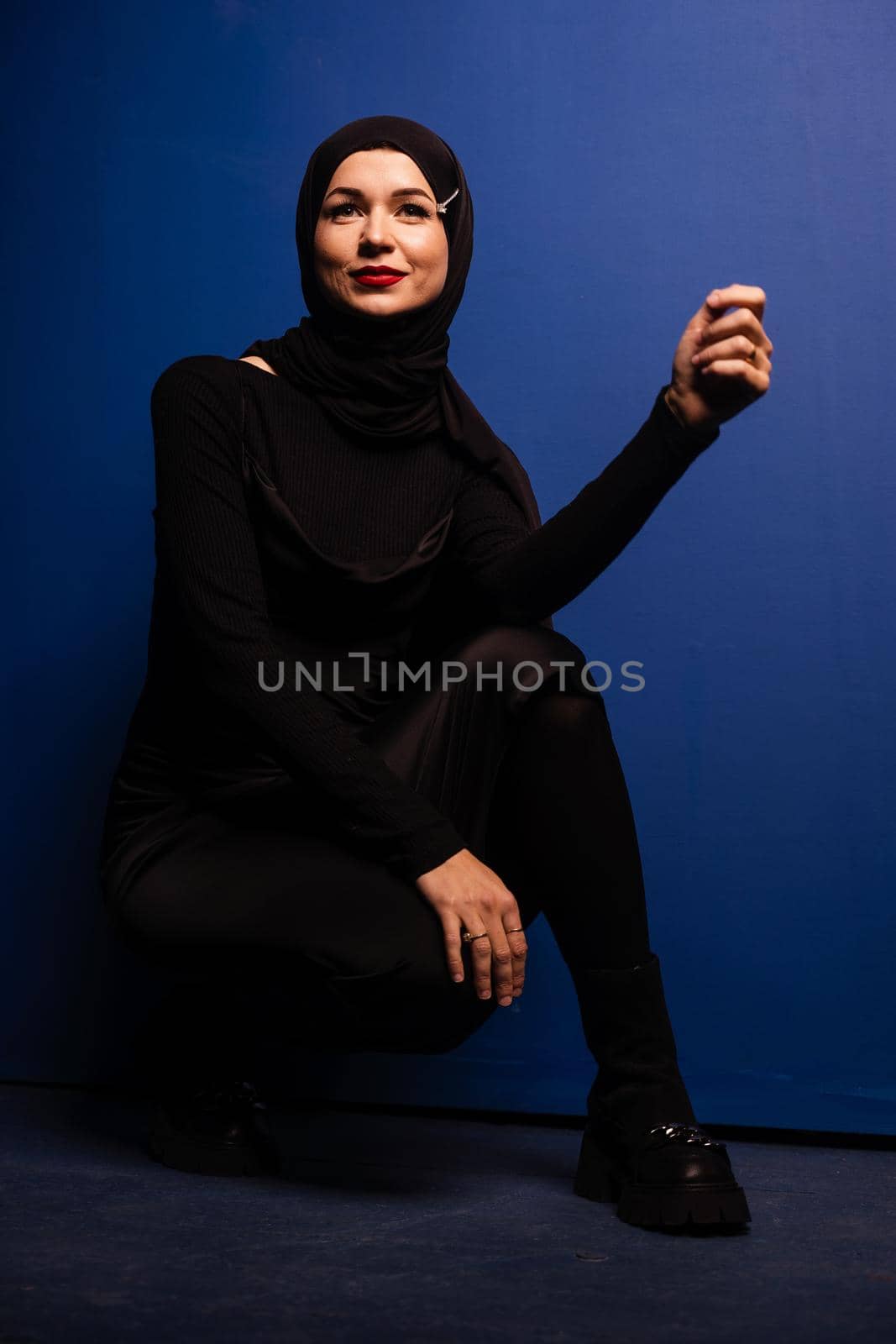 Fashion muslim model in black hijab is posing on blue background in studio. Islam religion. by Rabizo