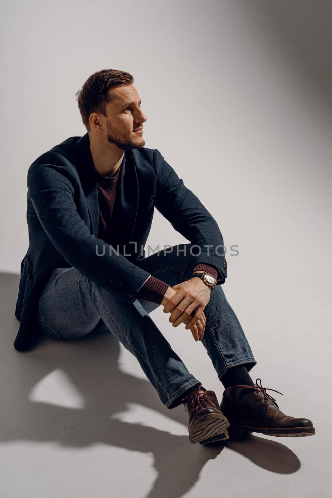 Fashion business man model posing in the studio. Confident male weared casual suit by Rabizo