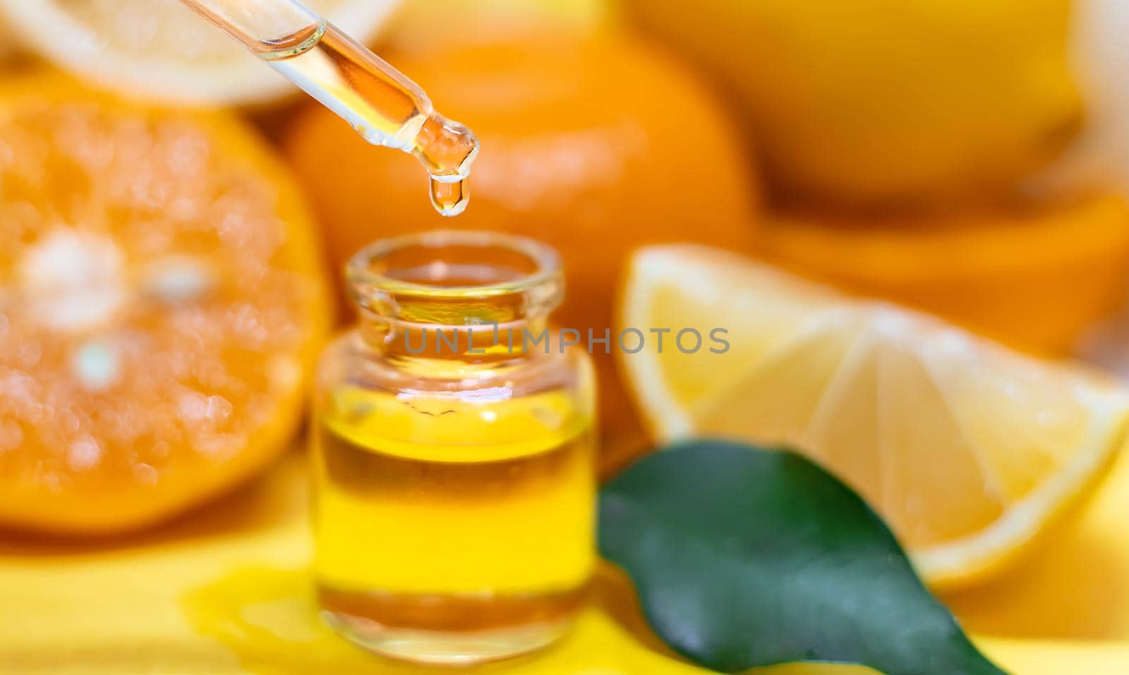 orange essential oil on a yellow background. Selective focus.