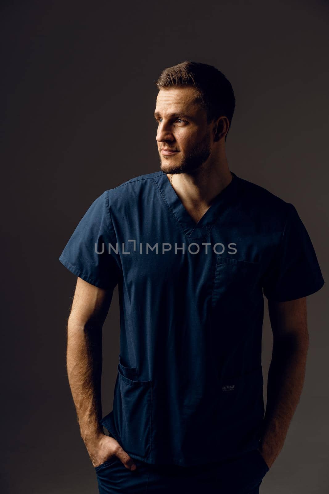 Surgeon weared in medical robe on dark background. Handsome doctor posing in studio