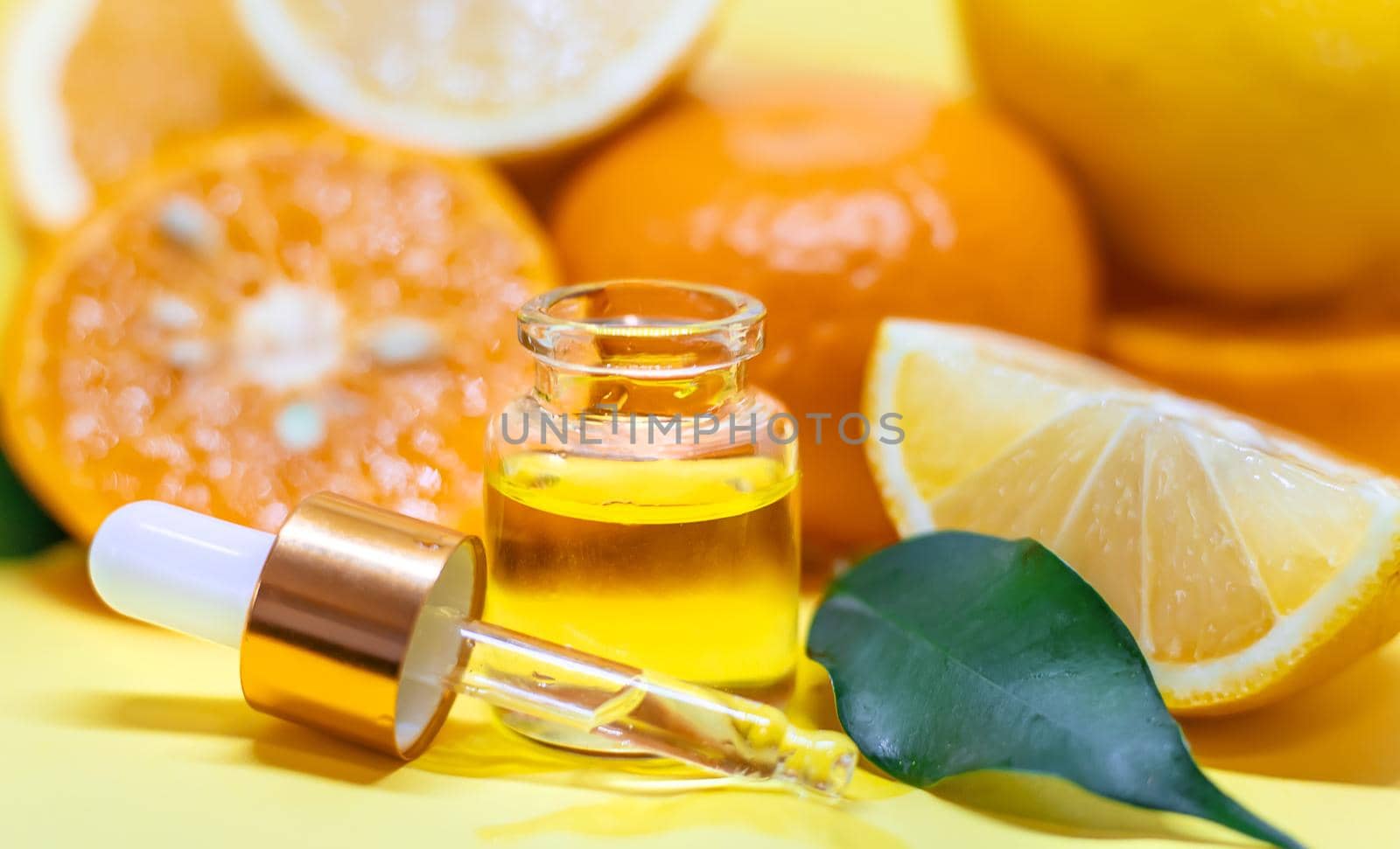 orange essential oil on a yellow background. Selective focus. by mila1784