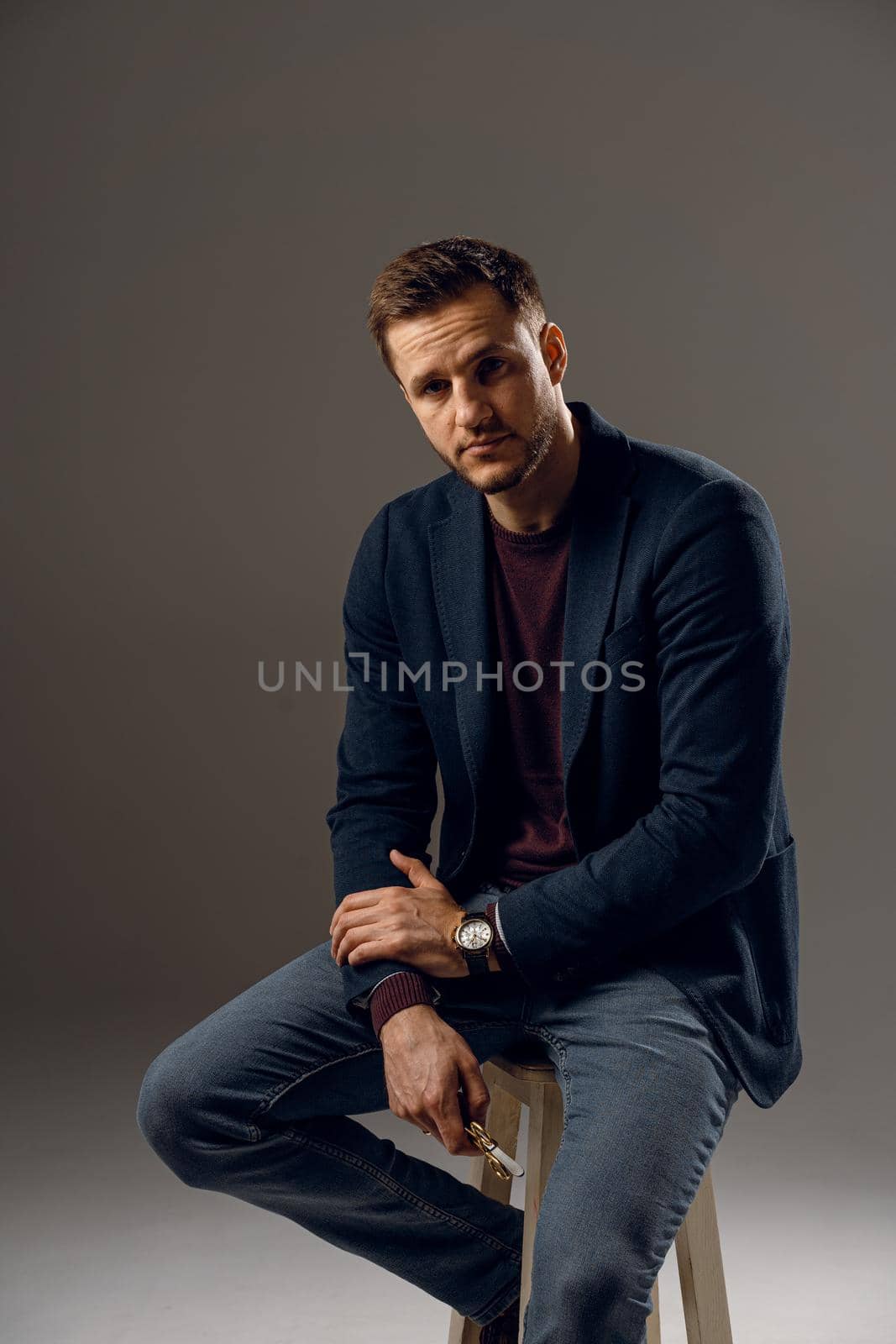 Handsome surgeon with needle holder and surgical knife weared casual suit in studio. Confident business man on dark background